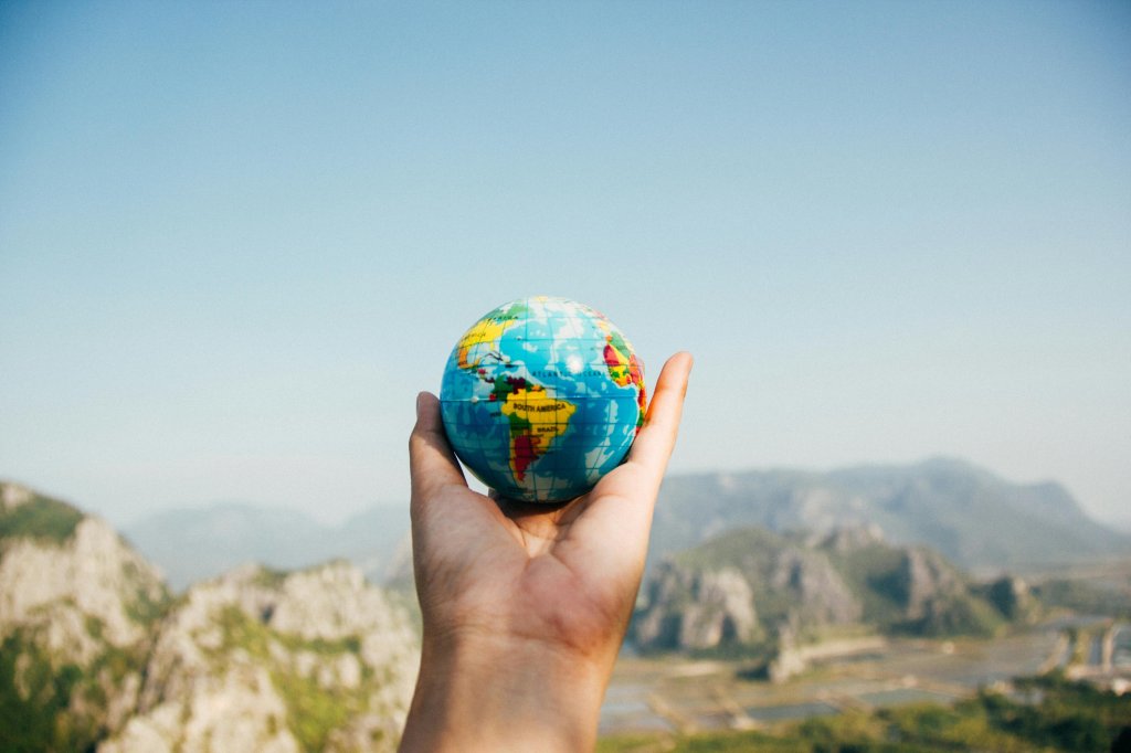 Photo by Porapak Apichodilok: https://www.pexels.com/photo/person-holding-world-globe-facing-mountain-346885/.