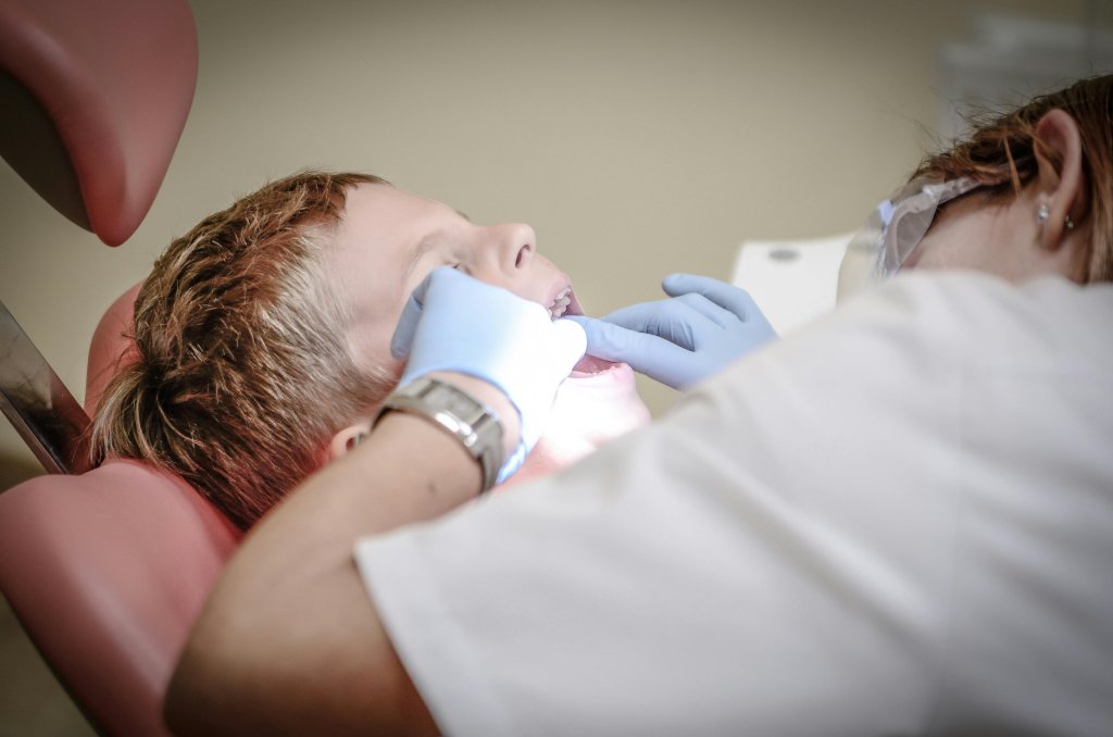 Photo by Pixabay: https://www.pexels.com/photo/dentist-woman-wearing-white-gloves-and-white-scrubsuit-checking-boy-s-teeth-52527/.